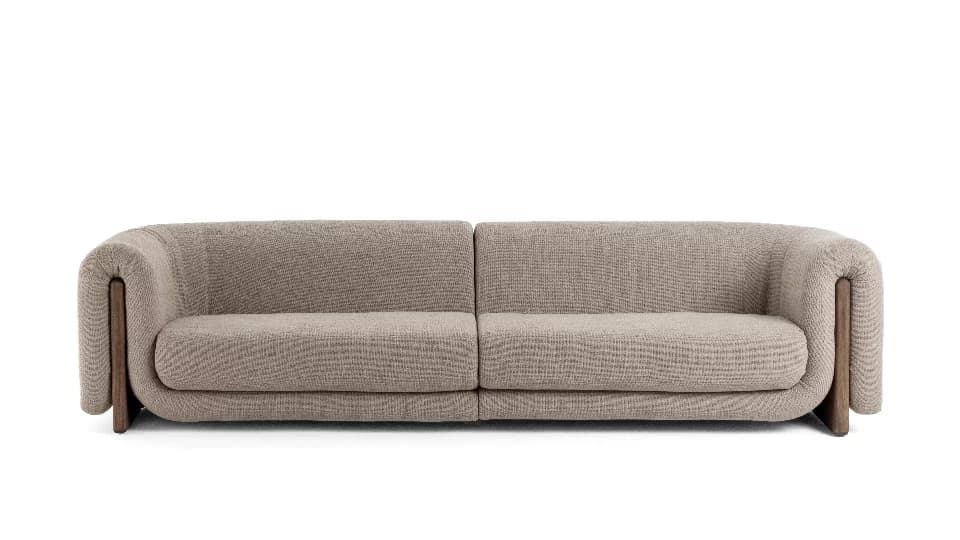 A contemporary modular two-seater sofa upholstered in a light beige/taupe textured fabric, featuring distinctive rounded arms that integrate with exposed dark wood side panels. The sofa is composed of two identical sections placed side-by-side, creating a unified long seating piece. It has a low profile with clean lines and soft, inviting forms. — 3D model
