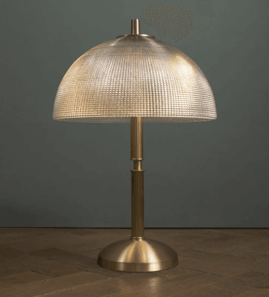 A modern table lamp featuring a polished brass finish base and a distinctive textured, off-white dome-shaped shade. The lamp has a cylindrical, fluted column connecting the base to the shade, with a small brass finial at the top of the shade. — 3D model