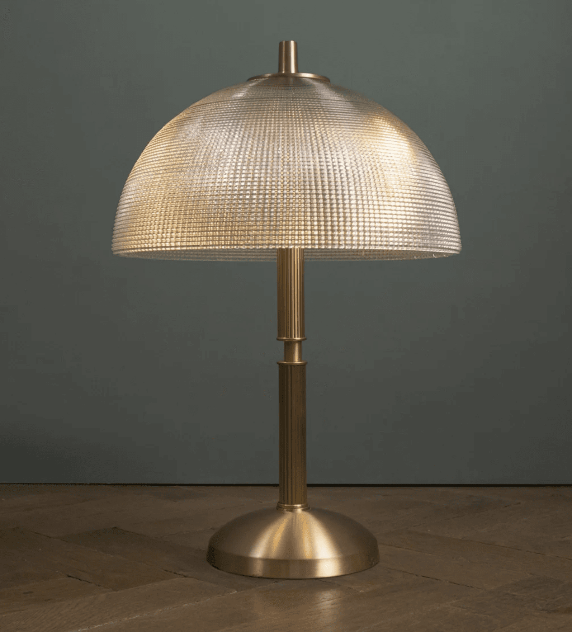 A modern table lamp featuring a polished brass finish base and a distinctive textured, off-white dome-shaped shade. The lamp has a cylindrical, fluted column connecting the base to the shade, with a small brass finial at the top of the shade. — 3D model