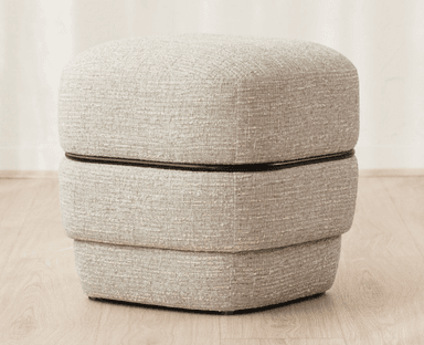 A contemporary, rectangular upholstered ottoman featuring a stacked, three-tiered design. The entire piece is covered in a light gray, highly textured fabric. A thin, dark (likely black) accent band visually separates the top cushion from the middle section, adding a distinct linear detail. The ottoman has soft, rounded edges and a minimalist aesthetic. — 3D model
