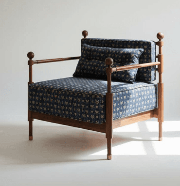 A contemporary armchair featuring an exposed dark wood frame with distinctive turned vertical posts and horizontal armrests, complemented by removable cushions upholstered in a vibrant dark blue and gold patterned fabric. The chair includes a seat cushion, back cushion, and a smaller lumbar cushion. The frame's legs are tapered and finished with small brass caps. — 3D model