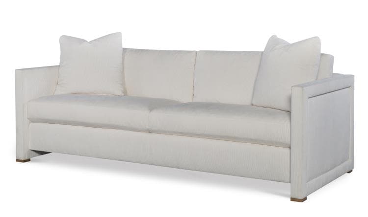 A white upholstered sofa with a clean-lined design. It features a three-cushion seat and back, with two rectangular throw pillows placed on either end. The sofa has straight, boxed arms and a low-profile base with visible wooden feet. The upholstery has a subtle textured pattern. — 3D model