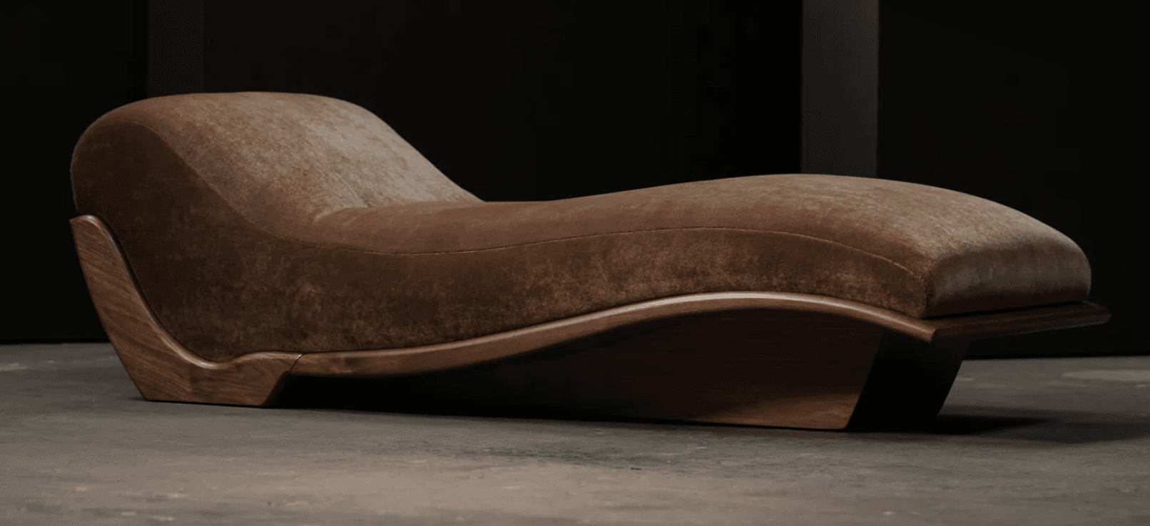 A modern chaise lounge featuring a distinctive ergonomic S-curve design. It consists of a plush, upholstered top in a brown, velvety fabric, supported by a sculptural wooden frame and base. The wood exhibits a dark, rich tone with a polished finish, highlighting its natural grain and elegant, flowing lines. The design emphasizes comfort and aesthetic form, suggesting a luxurious and contemporary piece. — 3D model