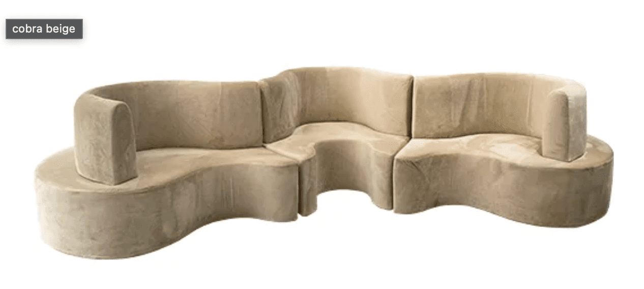 A modular, curved sofa with a sinuous, organic form. It appears to be upholstered in a soft, plush fabric and is composed of several interlocking sections. The design features rounded edges and a continuous, flowing silhouette, suggesting a contemporary or art deco influence. The sofa lacks visible legs, giving the impression it sits directly on the floor. — 3D model