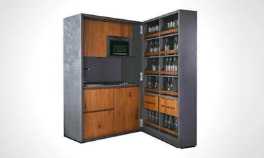 A compact, self-contained kitchen and bar unit designed to be concealed within a cabinet. The exterior features a dark grey, textured finish, opening to reveal a functional kitchenette on one side and extensive beverage storage on the other. The kitchenette includes an integrated microwave, a stovetop, a sink, and wooden storage drawers, while the bar section provides specialized shelving for bottles and glasses. — 3D model