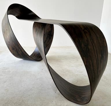 A sculptural console table with a continuous, ribbon-like form, crafted from a dark, heavily-grained wood veneer. — 3D model