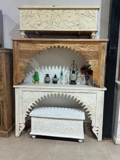 A narrow console table featuring a distinctive arched front intricately carved with floral and vine motifs, presented in a distressed whitewashed wood finish. It has a flat rectangular top and stands on small spherical feet. — 3D model