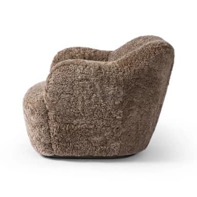 A plush, upholstered armchair with a rounded, organic silhouette. The piece features a thick, textured covering resembling sheepskin or a similar natural fiber, providing a soft and inviting appearance. The armrests are integrated into the body of the chair, flowing seamlessly into the back and seat. The base is low and broad, contributing to its sturdy and comfortable design. — 3D model