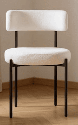 A modern accent chair with a black metal frame and a plush, textured cream-colored upholstery. The seat is round and thickly padded, and the backrest is a gently curved, low profile with a cylindrical armrest integrated into one side. The legs are slim and angled. — 3D model