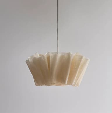 A modern pendant light featuring a cream-colored, pleated fabric shade, suspended by a dark cord. The shade has a distinctive scalloped or wavy edge, creating a soft, diffused light. — 3D model