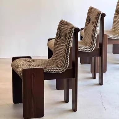 A modern accent chair featuring a robust, dark stained wooden frame with a block-like aesthetic. The seat and backrest are upholstered in a textured, woven fabric with a distinct beige and brown geometric pattern, exhibiting tufting details. — 3D model