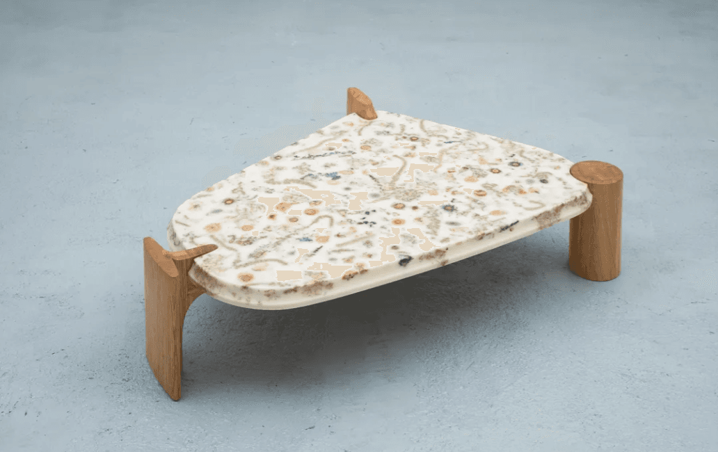 A unique side table with an irregularly shaped top and wooden legs. The tabletop appears to be made of a white composite material with embedded dried botanical elements such as flowers and leaves. The legs are cylindrical at the top and transition into a flared, curved support structure. — 3D model