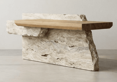A contemporary coffee table featuring an asymmetrical design with a multi-part, rough-hewn travertine stone base and a smooth, rectangular wooden top. The light-colored wood slab rests on and extends beyond the travertine elements, creating a dynamic visual contrast. — 3D model