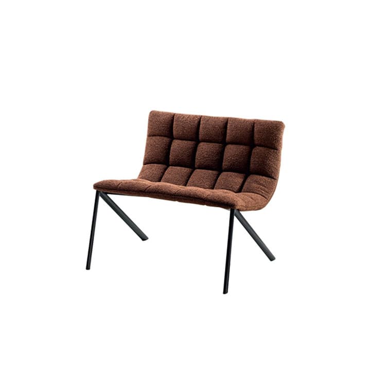 A modern armchair with a low profile, featuring a quilted upholstered seat and backrest supported by slender, angled metal legs. The upholstery has a textured, possibly boucle or shag, finish in a deep brown color. The seat and back are integrated into a single curved form, offering a contemporary aesthetic. — 3D model