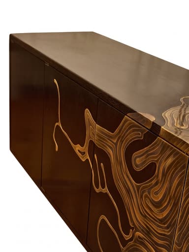 A long, rectangular credenza crafted from dark-stained wood, featuring multiple cabinet doors. The facade is adorned with a striking abstract brass inlay design that spans across the panels, creating a dynamic, flowing, topographic-like pattern. The credenza rests on a recessed plinth base. — 3D model