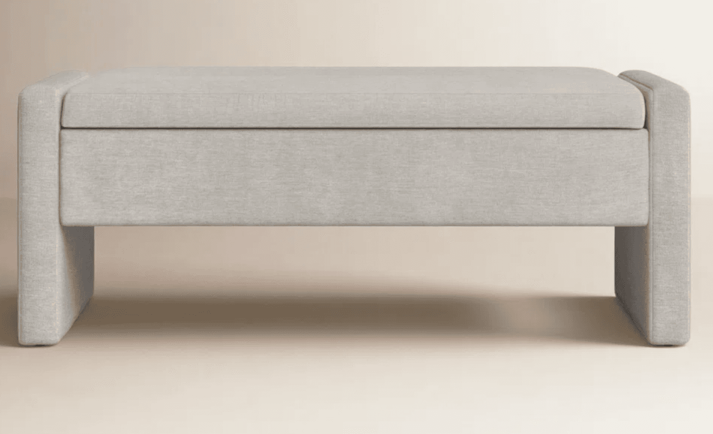 An upholstered rectangular storage ottoman with a lift-top, entirely covered in a light grey fabric, featuring integrated block-style legs and a minimalist design. — 3D model