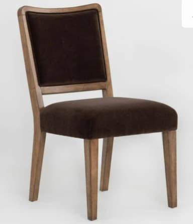 A contemporary armless dining chair featuring a light-toned wooden frame with a gently curved top rail on the backrest. The seat and backrest are upholstered in a dark brown, plush fabric, likely velvet. The chair stands on four sturdy, slightly tapered wooden legs. — 3D model