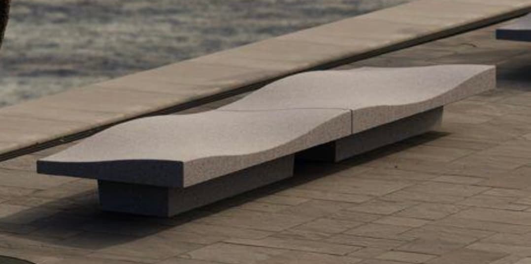 A long, single-person chaise lounge constructed from a gray, textured, stone-like material, likely concrete or a similar composite. The lounge features an undulating, ergonomic surface designed for reclining comfort, and appears to be composed of two distinct sections that fit together to form the complete piece. It has a minimalist, sculptural aesthetic. — 3D model