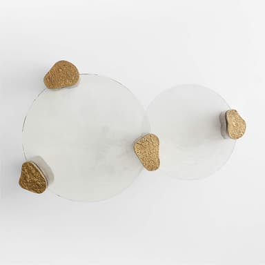 A contemporary coffee table with a circular, smoked glass top supported by four uniquely shaped, textured metallic legs. The legs appear to be cylindrical with irregular, rough surfaces and are finished in a bronze-like hue. The overall design is minimalist yet impactful, with the textured legs contrasting with the smooth glass. — 3D model