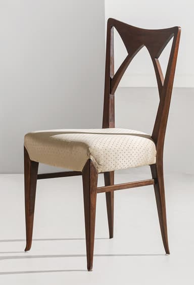 A Mid-Century Modern style dining chair featuring a dark wood frame and an upholstered seat. The backrest is distinctive, showcasing an open, geometric design with angular cutouts. The legs are tapered, and the seat is covered in a light, possibly cream-colored fabric with a subtle dotted pattern. — 3D model