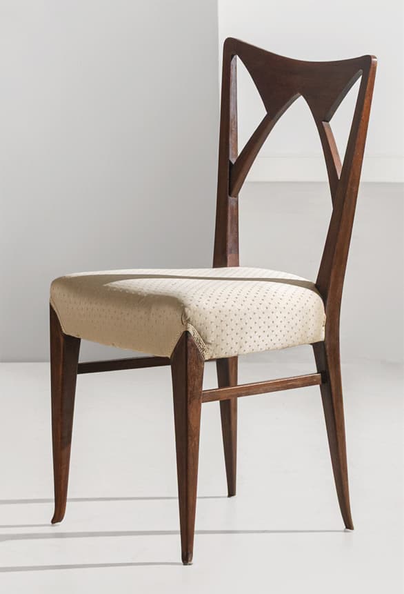 A Mid-Century Modern style dining chair featuring a dark wood frame and an upholstered seat. The backrest is distinctive, showcasing an open, geometric design with angular cutouts. The legs are tapered, and the seat is covered in a light, possibly cream-colored fabric with a subtle dotted pattern. — 3D model
