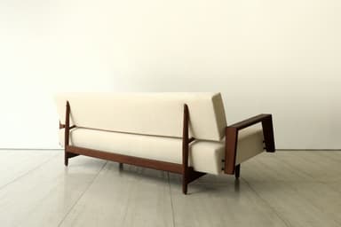 A minimalist two-seater loveseat featuring a cream-colored upholstered seat and backrest, supported by a dark, possibly walnut, wooden frame with open, U-shaped armrests and slender tapered legs. — 3D model