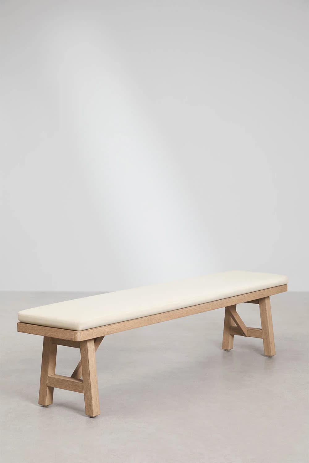 A minimalist bench with a light wood frame and a cream-colored cushioned seat. The frame features a simple, angular design with two A-frame legs connected by a horizontal support. The cushioned seat appears to be upholstered. — 3D model