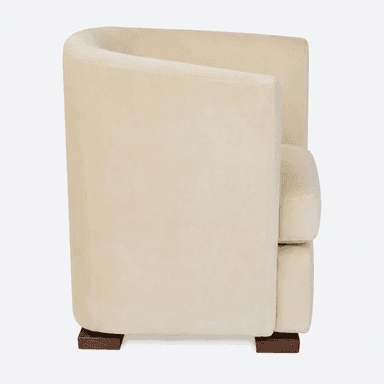 A contemporary club armchair, fully upholstered in a cream or light beige fabric, likely velvet or chenille. It features a rounded backrest that flows into integrated armrests, providing a cohesive and enclosed form. The seat cushion is separate and removable. The chair stands on four short, square block feet made of dark wood, providing a stable base and a subtle contrast to the light upholstery. — 3D model