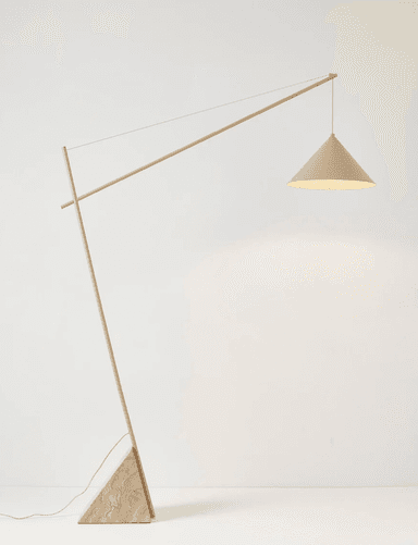 A modern floor lamp with a distinctive, minimalist design. It features a tall, slender stem that extends at an angle, supporting a conical lampshade suspended by a thin wire. The base is a substantial, triangular prism made of veined stone. — 3D model