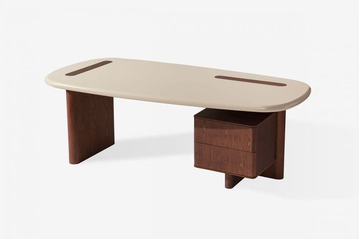 A modern executive desk featuring an elongated oval or oblong desktop with rounded edges, supported by a thick, dark wood pedestal leg on one side and an integrated two-drawer storage cabinet on the other. The desktop is a light cream or beige color, contrasting with the dark brown wood of the base and drawers. There are two recessed, elongated wood strips on the desktop surface, mirroring the shape of the top. The overall design is minimalist and sculptural. — 3D model
