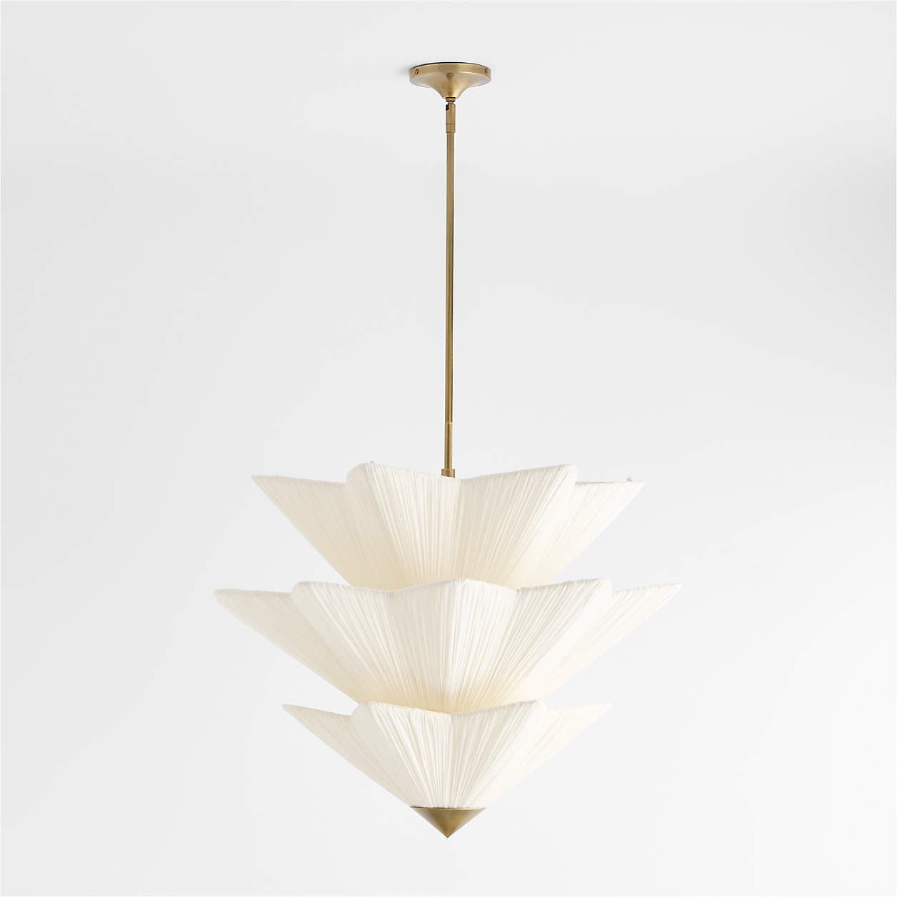 A sophisticated three-tiered pendant light featuring pleated off-white fabric shades suspended from a brass rod and canopy. Each tier consists of multiple pleated segments arranged to create a distinct, fanned silhouette, reminiscent of stylized floral petals or Art Deco design elements. The brass hardware provides a subtle contrast to the soft texture of the fabric shades, culminating in a decorative brass finial at the bottom. — 3D model