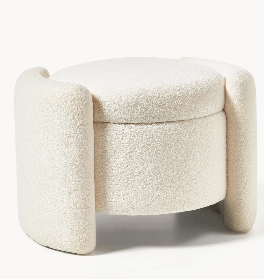 A cylindrical ottoman with a rounded top, upholstered in a textured cream-colored fabric. It features unique, curved armrest-like supports on either side, extending upwards from the base. — 3D model