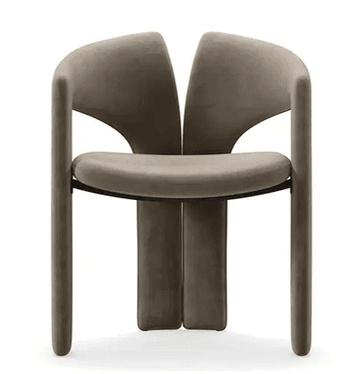 A contemporary armchair featuring a fully upholstered form in a neutral taupe or greige velvet-like fabric. The design incorporates a distinctive U-shaped armrest that flows into the front legs, paired with a separate, slightly curved backrest that extends downwards to form the rear legs. The entire structure is seamless and upholstered, giving it a plush, monolithic appearance. — 3D model