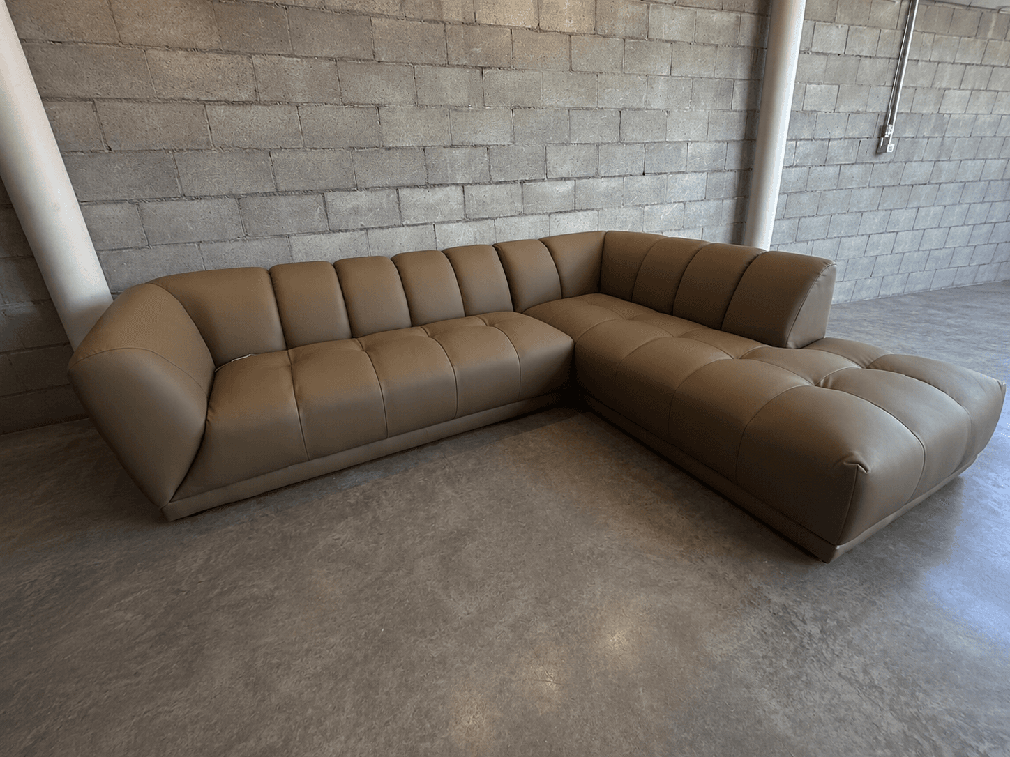 An L-shaped sectional sofa with tan upholstery, featuring individual segmented backrests and seat cushions, and an integrated chaise lounge on one end. It has a low-profile design. — 3D model