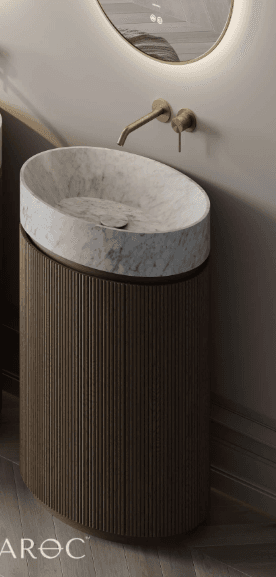 A freestanding vanity with a carved marble basin and a fluted wooden cabinet. The basin is oval-shaped and appears to be made of white marble with grey veining. The cabinet is cylindrical with vertical fluting and is finished in a dark wood tone. A wall-mounted faucet with a brass finish is visible above the basin. — 3D model