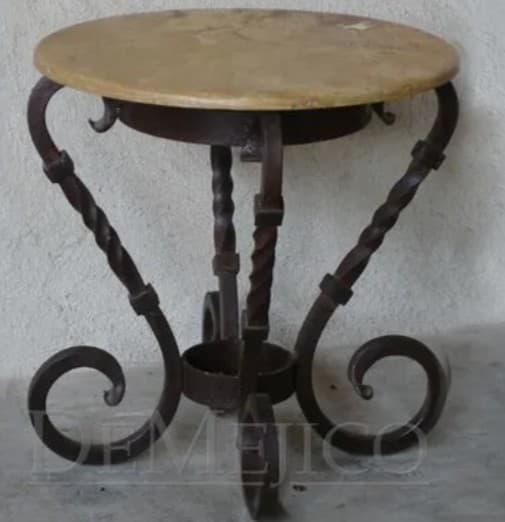 A round-top side table with a cream-colored, possibly stone or composite, surface. The base is constructed from dark brown wrought iron, featuring twisted columnar legs that transition into decorative scrollwork near the floor. The design suggests a rustic or traditional aesthetic. — 3D model