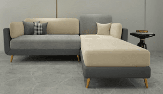 An L-shaped sectional sofa featuring a multi-tone fabric upholstery in shades of gray and beige/cream. The sofa includes a prominent chaise lounge section and is supported by slender, tapered wooden legs. It comes with two accent pillows, one solid gray and one black and white plaid. — 3D model
