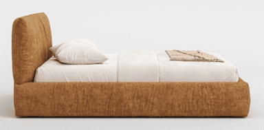 A king-size upholstered bed frame with a plush headboard featuring a ruched or gathered fabric design. The bed is dressed with white bedding, a decorative pillow, and a quilted throw blanket. It sits on a solid base and is flanked by two small, modern side tables, one holding a vase with floral sprigs and the other a cup and saucer. — 3D model