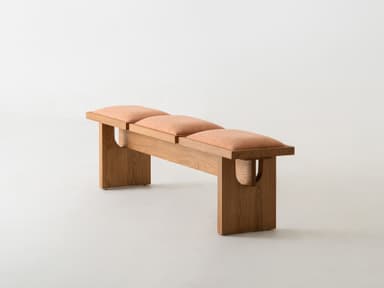 A modern bench crafted from light-toned oak wood, featuring a minimalist design. The bench is equipped with three individual, rectangular upholstered cushions in a textured peach-colored fabric, set within the wooden frame. The frame consists of a sturdy base and two plank-style legs. — 3D model