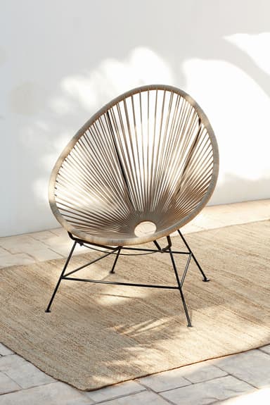 An Acapulco-style lounge chair featuring an egg-shaped seat crafted from radially woven beige or tan synthetic cord. The seat is supported by a minimalist, four-legged black metal frame, designed for comfort and outdoor durability. — 3D model