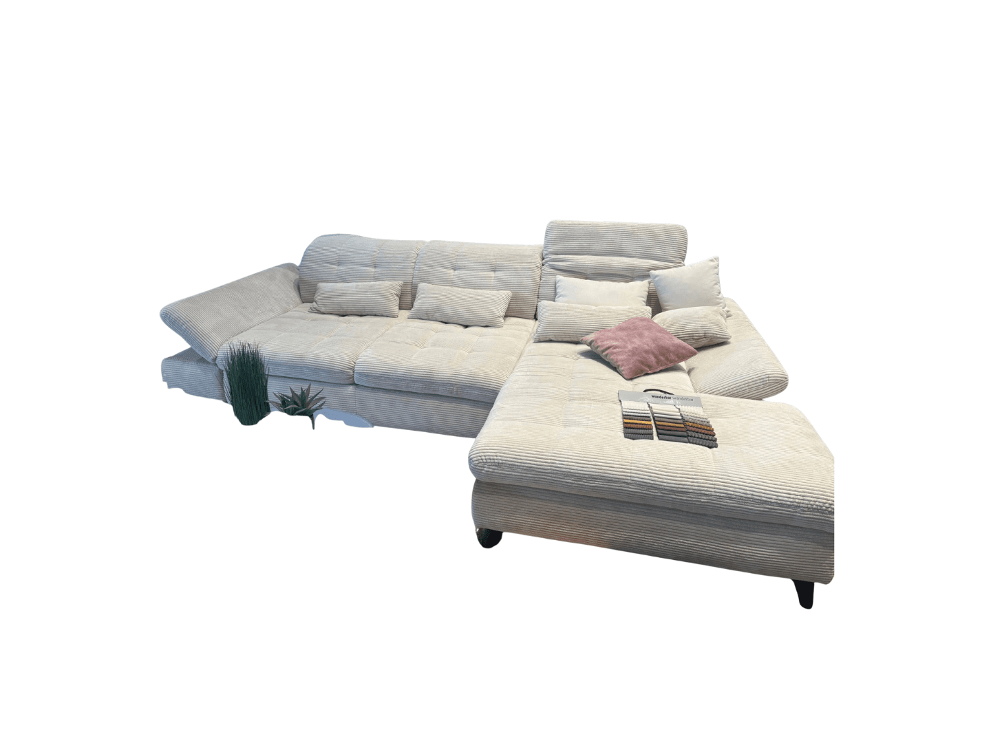 A large, sectional sofa with a corduroy-like fabric texture. The sofa is a light beige or cream color and features tufted cushions. It includes several throw pillows of varying sizes and colors (white, light pink). A swatch book with fabric samples is placed on one of the seating sections. The sofa has a chaise lounge component and appears to be a modular design. — 3D model