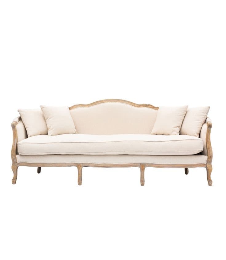 A classic French Provincial style sofa featuring an exposed, carved natural wood frame and upholstered in a light, neutral fabric with multiple loose back cushions. — 3D model
