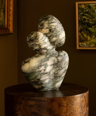 An abstract, biomorphic sculpture made from veined marble. The piece features a curvilinear, organic form with a wider base tapering up to two rounded, interlocking shapes at the top. The marble exhibits natural patterns of green, grey, and white veining, and the entire surface is highly polished. — 3D model