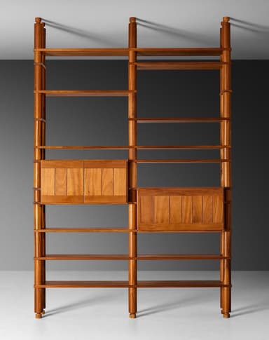 A tall, free-standing shelving system crafted from teak wood, featuring multiple open shelves and two integrated closed cabinet modules. The structure is defined by cylindrical vertical posts with turned finial details at the top and bottom, which support adjustable or fixed horizontal shelves. The cabinet fronts feature vertical slatted panels, contributing to its mid-century Italian aesthetic. — 3D model