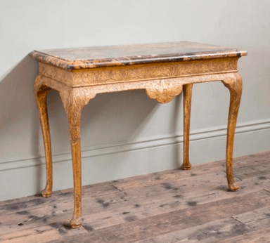 An ornate console table featuring a variegated marble top and a heavily carved giltwood frame. The table stands on four cabriole legs with carved detailing, and its apron is elaborately scalloped and embellished with relief carvings. The gilding shows signs of age and wear, contributing to its antique appearance. — 3D model