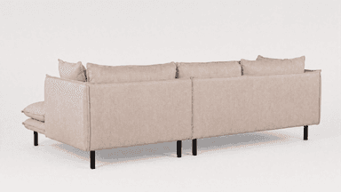 A contemporary sectional sofa, seen from the rear and side, upholstered in light beige/greige fabric with black metal legs. It features multiple loose back cushions and a low-profile design. — 3D model