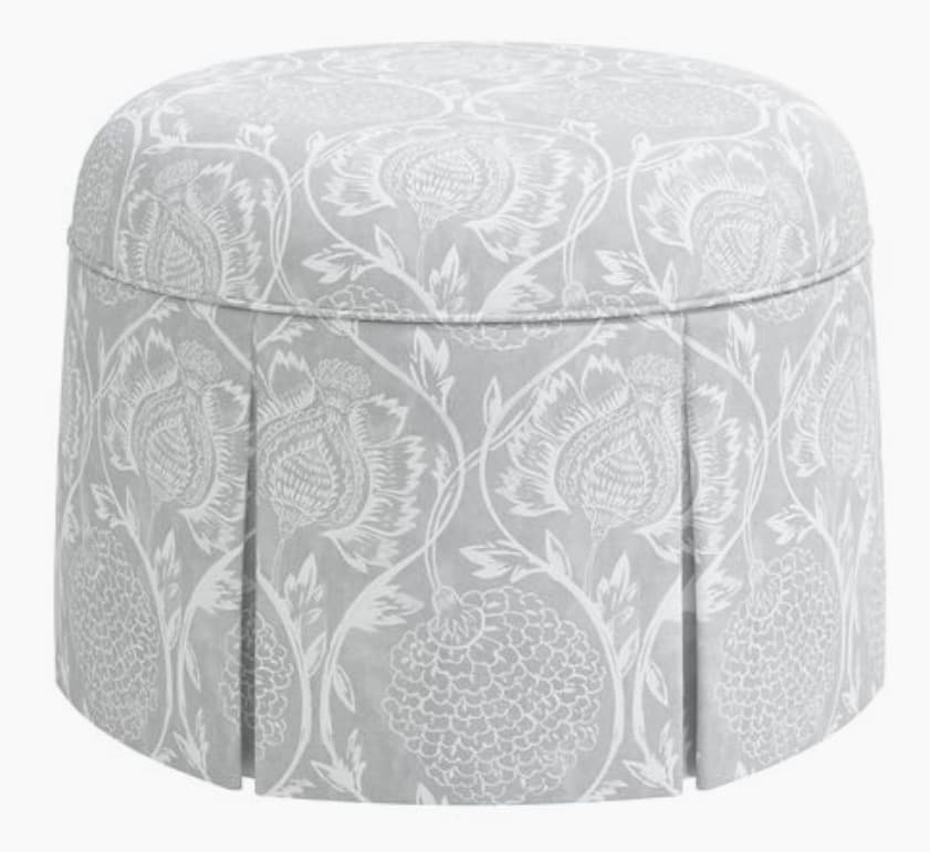 A round ottoman with a pleated skirt and a patterned upholstery. The top surface is slightly domed and features a floral pattern. The skirt has vertical pleats and is also adorned with a floral and foliage motif. — 3D model