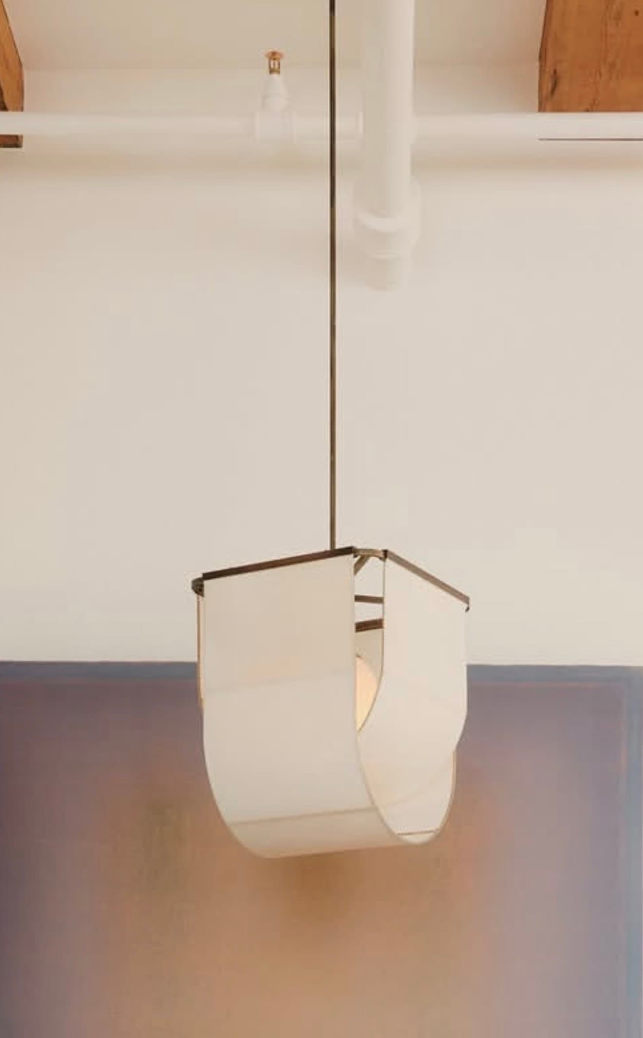 A modern pendant light featuring a geometric metal frame in a dark finish, encasing a softly curved, off-white fabric shade. The design allows for an exposed light source, creating a warm, diffused glow within a clean, architectural structure. — 3D model