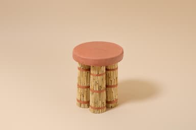 A small, round accent table featuring a flat, circular top made of reddish-brown terracotta. The base consists of three bundles of light-colored bamboo sticks, tied securely in multiple places with reddish-brown woven natural fiber. The legs appear to be cylindrical and provide a sturdy base for the rustic top. — 3D model