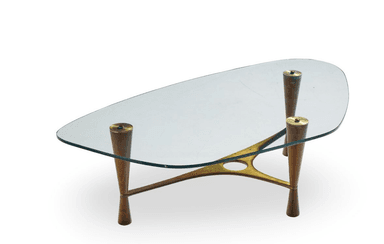 A glass-top coffee table with a distinctive mid-century modern design, featuring a sculptural brass frame and tapered wooden legs. — 3D model